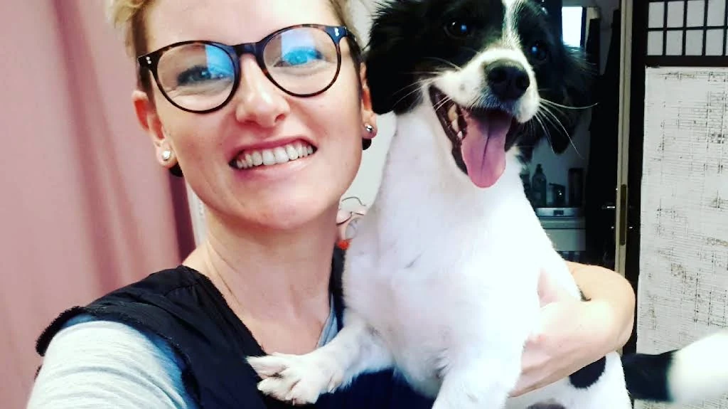 Originalaufnahme aus dem Wauzi-Salon: eine lächelnde Frau mit einem schwarzweißen Hund auf dem Arm